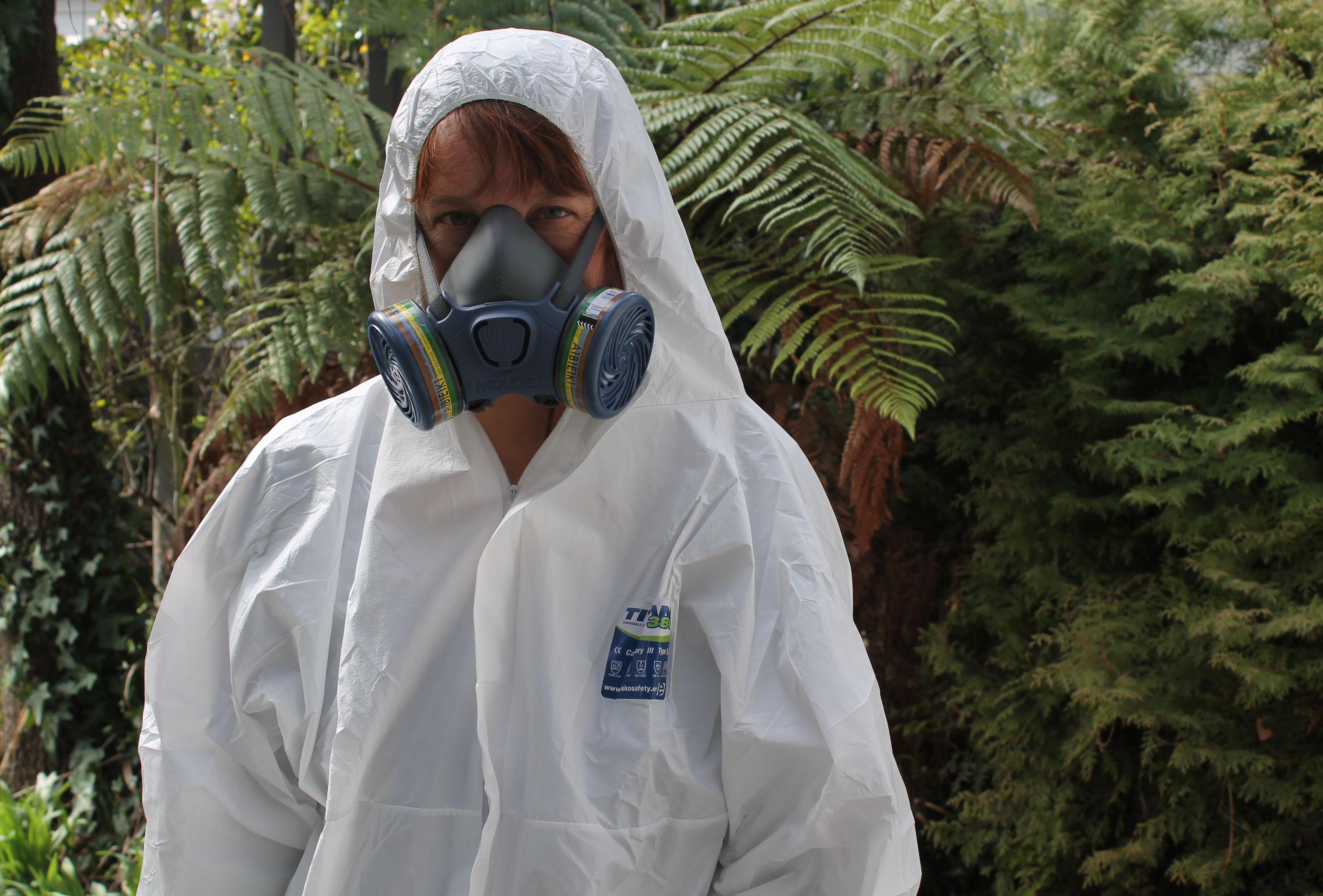 A photo of Katy Gosset wearing a mark and white protective suit and hood, ready to go into a meth house.