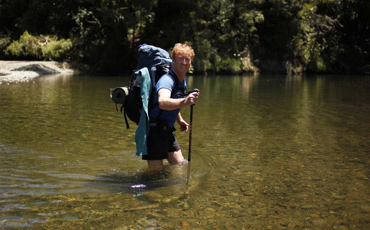 Geoff Chapple crossing a river on Te Araroa - New Zealand's Trail.