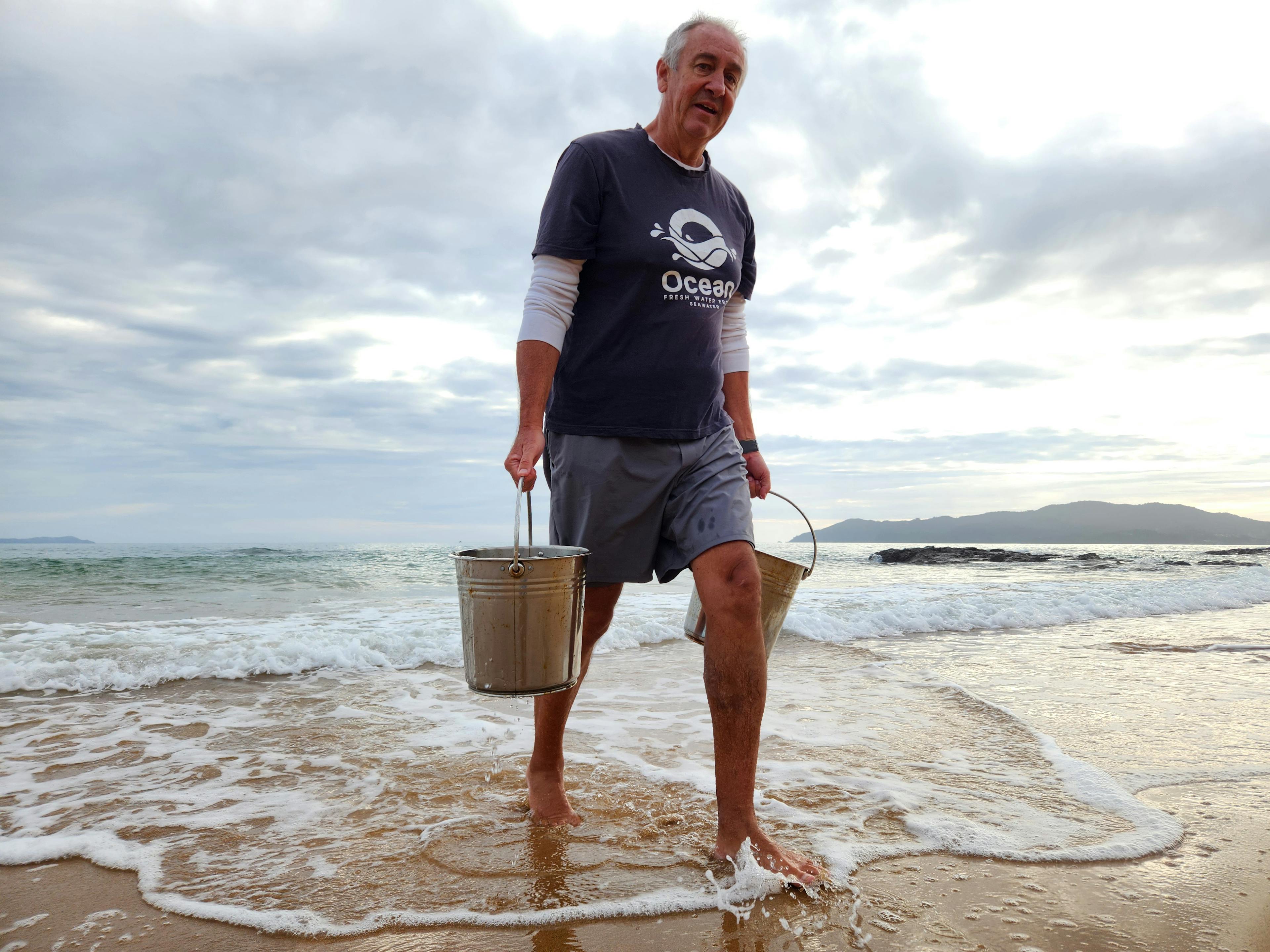 James collects seawater by hand from Cable Bay in Northland