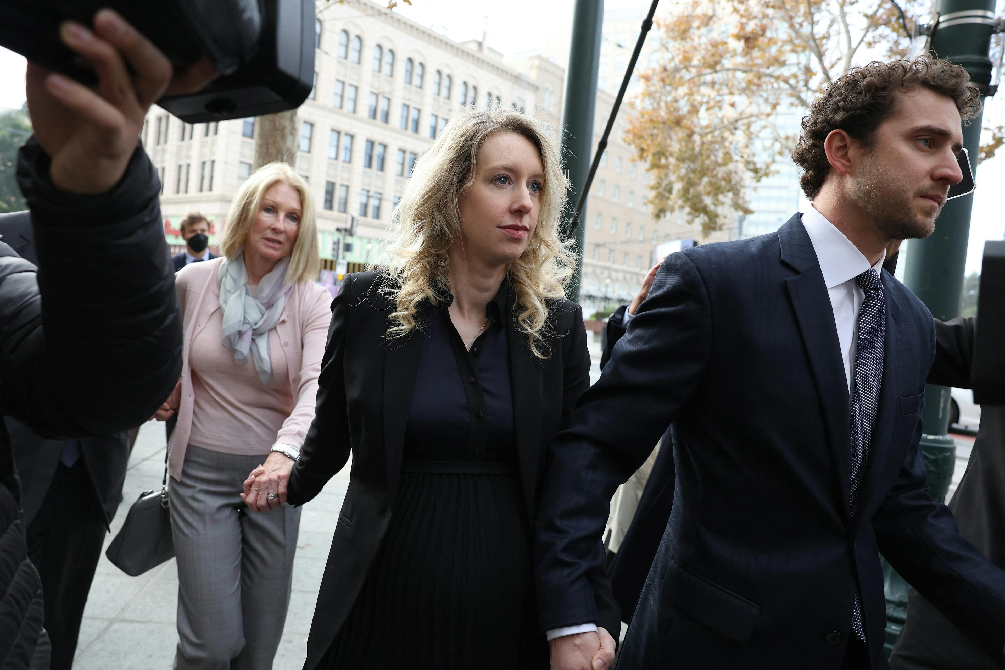 SAN JOSE, CALIFORNIA - NOVEMBER 18: Former Theranos CEO Elizabeth Holmes (C) arrives at federal court with her partner Billy Evans (R) and mother Noel Holmes on November 18, 2022 in San Jose, California. Holmes appeared in federal court for sentencing after being convicted of four counts of fraud for allegedly engaging in a multimillion-dollar scheme to defraud investors in her company Theranos, which offered blood testing lab services.   Justin Sullivan/Getty Images/AFP (Photo by JUSTIN SULLIVAN / GETTY IMAGES NORTH AMERICA / Getty Images via AFP)