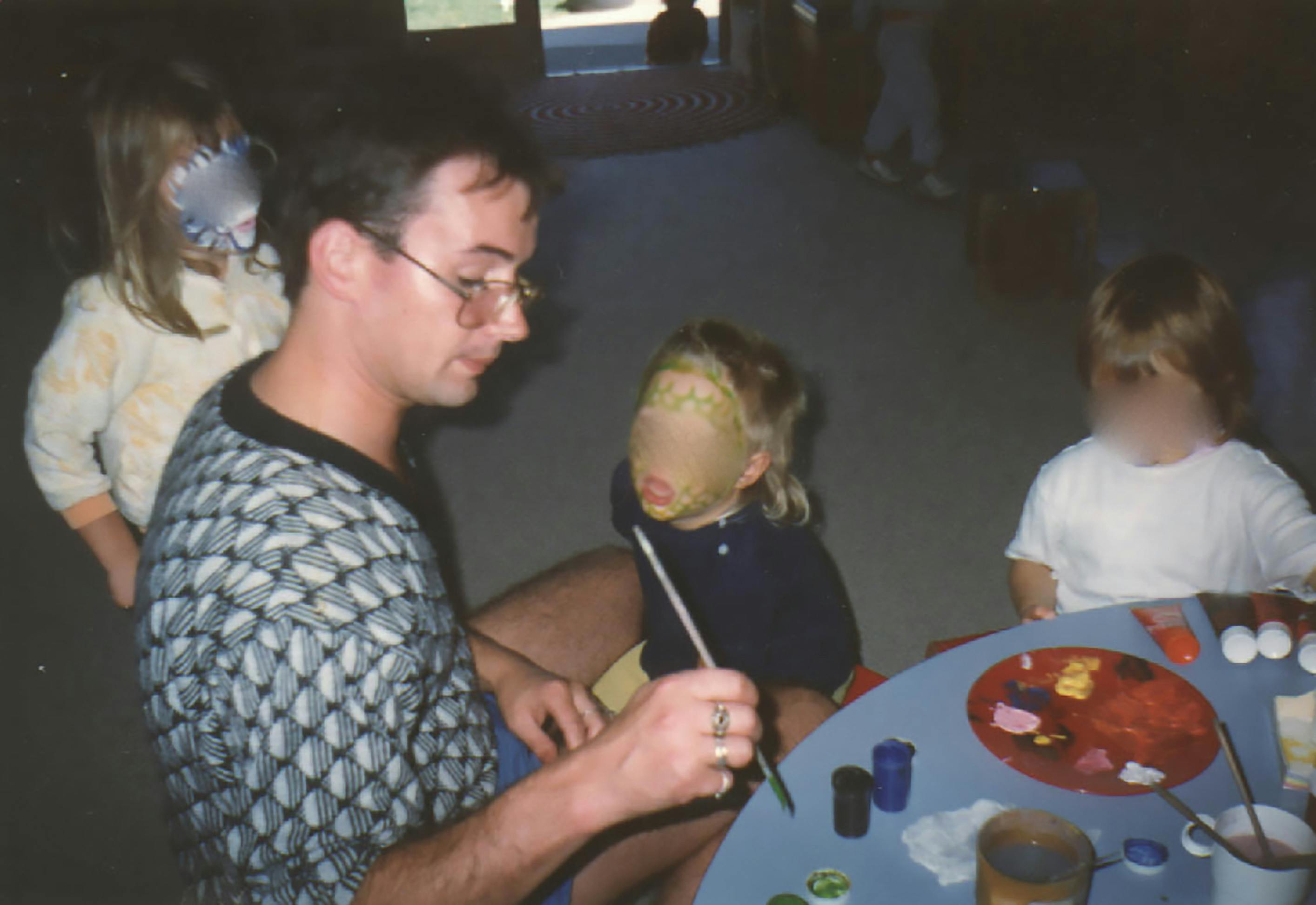 Peter Ellis painting faces at the Christchurch Civic Creche. The children's faces have been blurred.