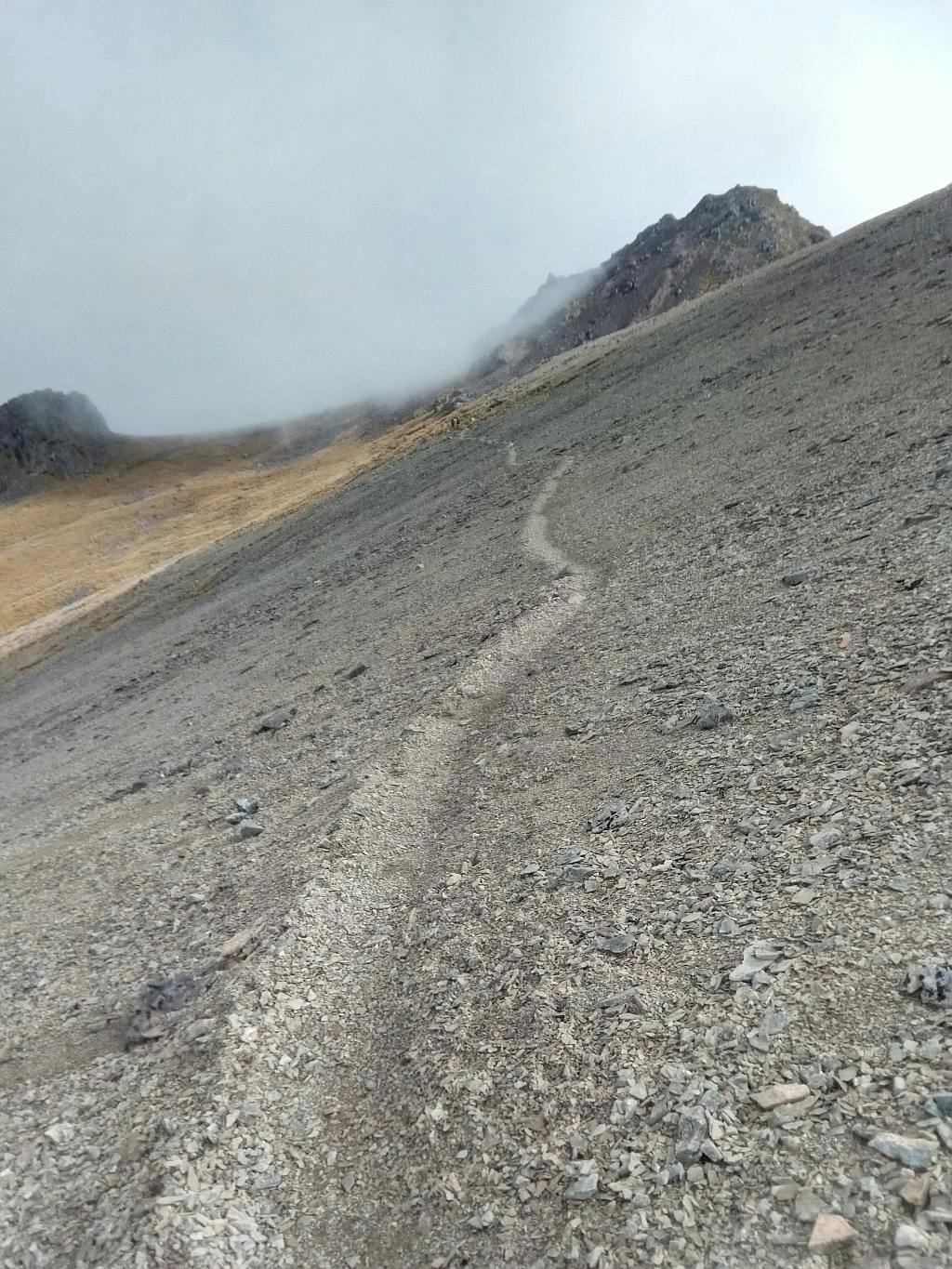 An image of a sheer scree slope with a barely-there trail on the side.