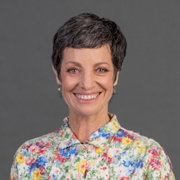 Smiling Sharon Brettkelly with a grey background