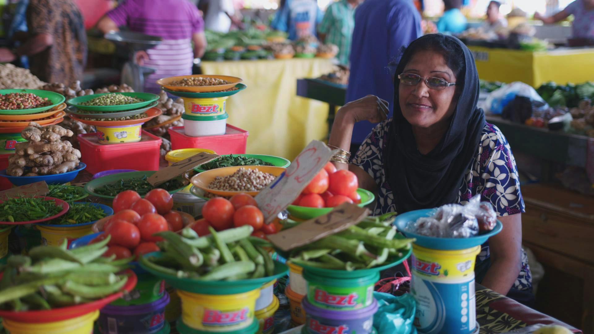 A Fijian Indian woman sits at her vibrant food stall at Suva Market