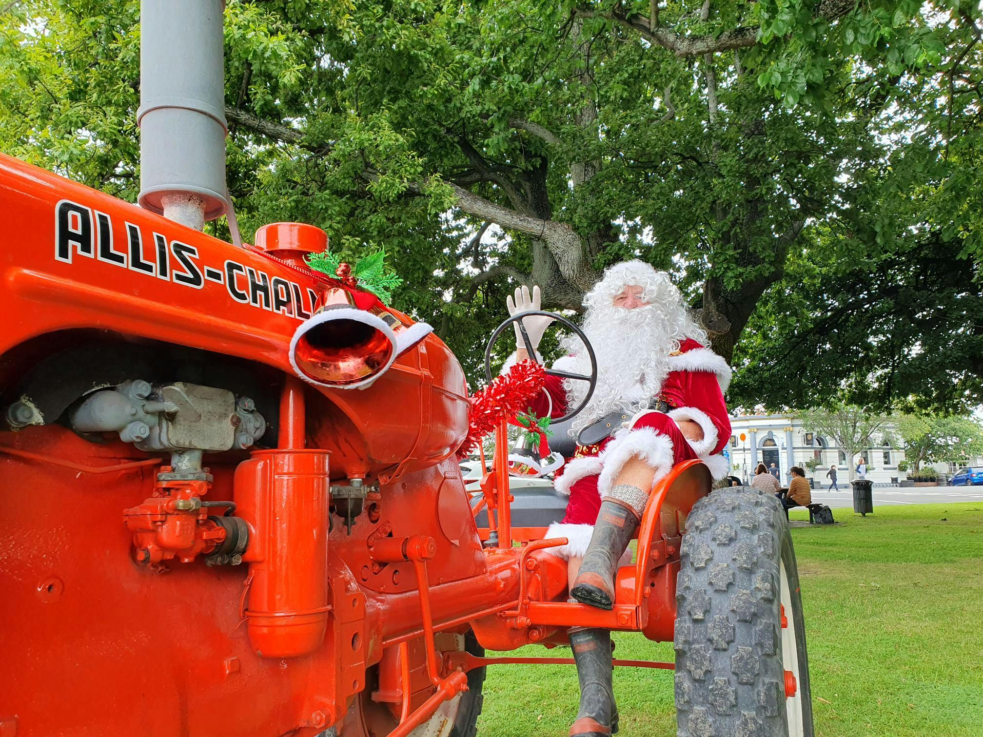 Santa waves hello on his big red tractor.