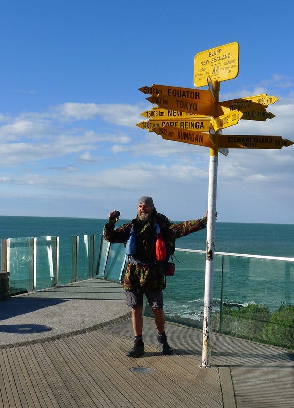 Bruce Hopkins poses underneath the Bluff signpost, the official end of Te Araroa.