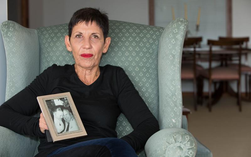 Janet Colby sits in her living room holding a picture of her parents.