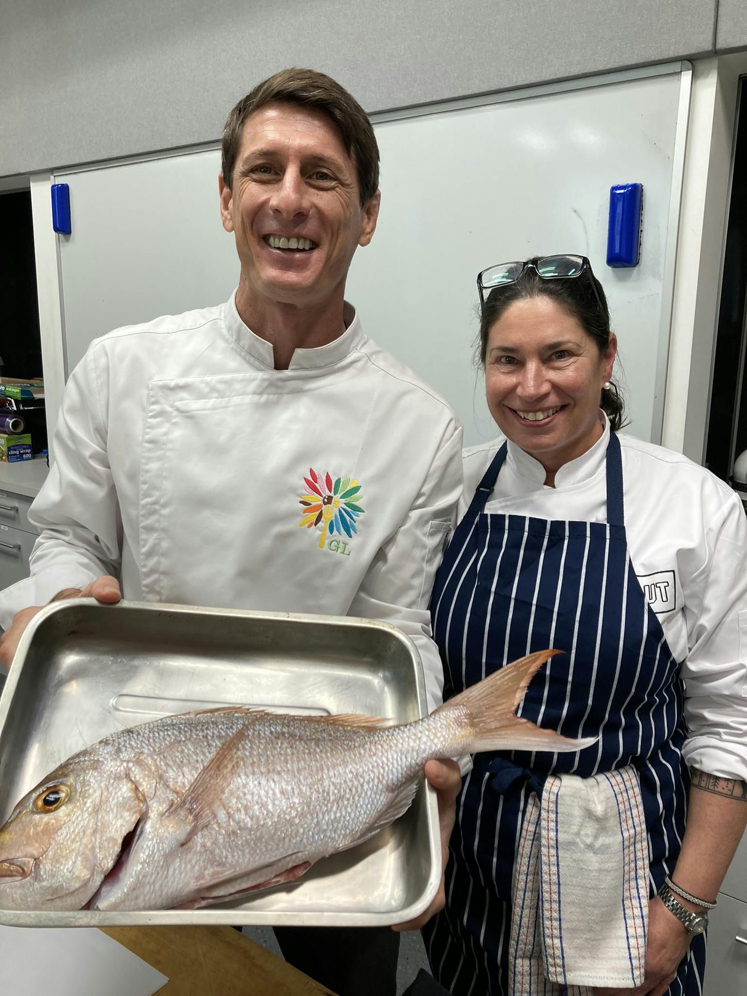 A head and shoulders shot of chef Gaby Levionnois (left) holding a dish with a fish on it and AUT's professor of Food Studies Tracy Berno (right)